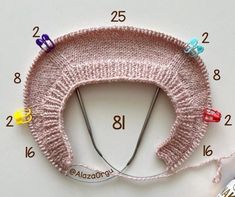 a knitted hat with pins and needles attached to it