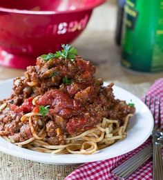 spaghetti with meat sauce and parsley on a plate next to a bottle of wine