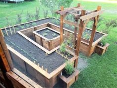 an outdoor garden area with raised wooden planter boxes and trelliss around it