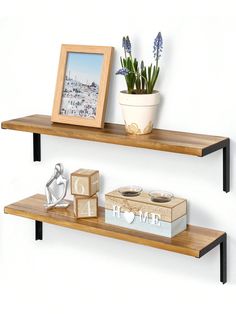 two wooden shelves with pictures and other items on them next to a potted plant