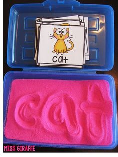 two plastic containers filled with pink sand and the word cat in it's center