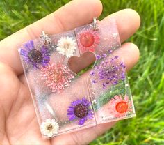 two small square earrings with flowers in the middle and one heart shaped dandelion