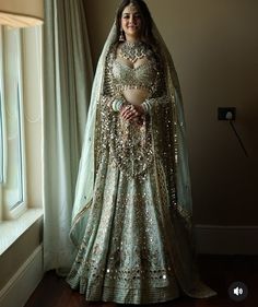 a woman in a bridal gown standing by a window