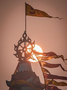 the sun is setting behind some flags on top of a building