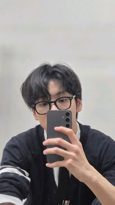 a young man taking a selfie in front of a mirror with his cell phone