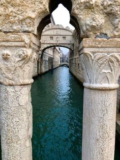 the water is blue and green in this city canal with stone pillars on either side