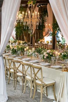 a long table is set up with white linens and greenery for an elegant wedding reception