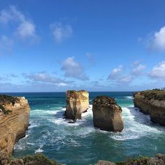 two large rocks sticking out of the ocean next to each other with waves crashing against them