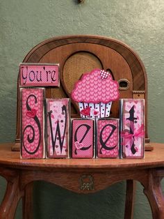 a wooden table topped with pink and white blocks that say you're sweeter