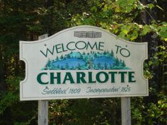 a welcome sign for charlotte in front of some trees