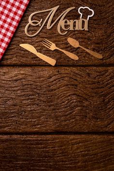 a wooden table topped with utensils next to a red and white checkered table cloth