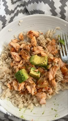 a white plate topped with rice and chicken next to a fork on a table cloth