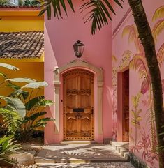 an entrance to a pink house with palm trees in the foreground and painted walls