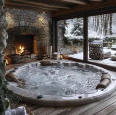 a large hot tub sitting in the middle of a wooden floored room next to a fire place