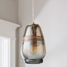 a glass light hanging from a ceiling in a room with white walls and trimmings