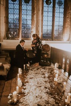 a man and woman are sitting on the floor with candles in front of them as they look at each other