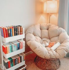 a room with a chair, bookshelf and lamp on the floor in front of it