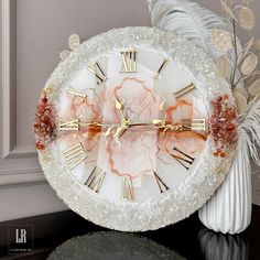 a white clock with gold hands and roman numerals on it's face