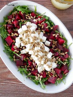 a salad with beets, feta cheese and pine nuts in a white bowl