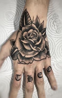 a hand with a rose tattoo on it and two small letters in front of it