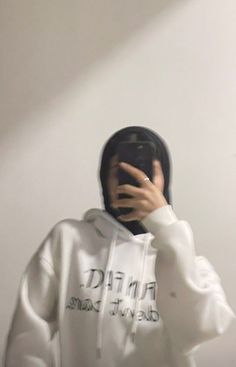 a person wearing a white hoodie taking a selfie