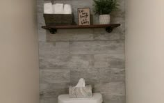 a white toilet sitting in a bathroom next to a wooden shelf with towels on it