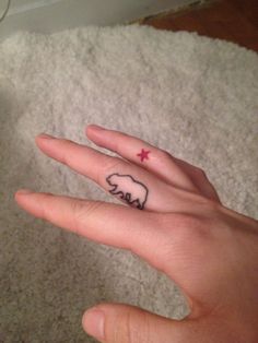 a person's hand with a small elephant tattoo on the middle finger and a star in the middle