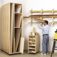 a man standing next to a wooden shelf with shelves and drawers on top of it