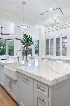 a large white kitchen with an island in the middle and lots of windows on both sides