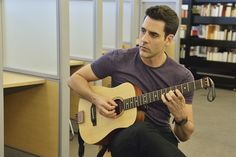 a man is playing an acoustic guitar in the library