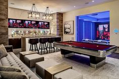 a living room with a pool table and bar in the backround next to couches