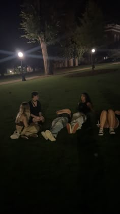 four people sitting on the grass at night