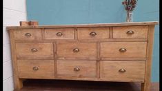 an old wooden dresser with many drawers and knobs on the bottom drawer, in front of a blue wall