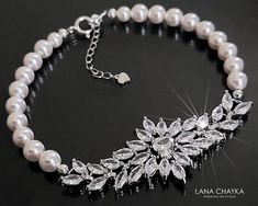 a white pearl necklace with crystal leaves and pearls on a black background, featuring the name lana chaka