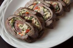 a white plate topped with rolls covered in meat and veggies on top of it