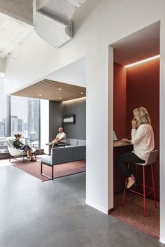 a woman sitting at a desk in an office with two men working on laptops