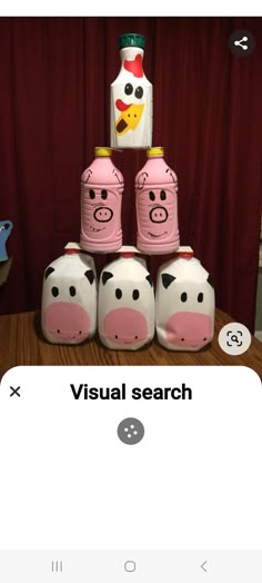 several pink piggy bank sitting on top of a wooden table next to a bottle