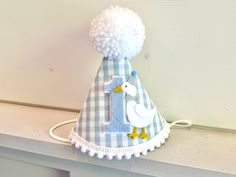 a blue and white party hat with a duck on it's side, sitting on top of a shelf