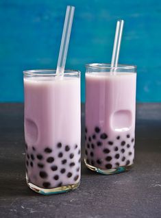 two glasses filled with bubble milk sitting next to each other on top of a table