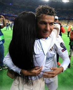 two soccer players hugging each other in the middle of a field with fans behind them