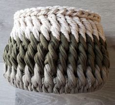 a close up of a woven basket on a wooden floor with white and green yarn