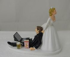 a bride and groom figurine sitting next to each other on a white surface