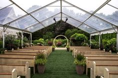 the inside of a church with rows of pews and plants in pots on each side