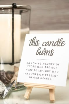 a sign sitting on top of a wooden easel next to a glass candle holder