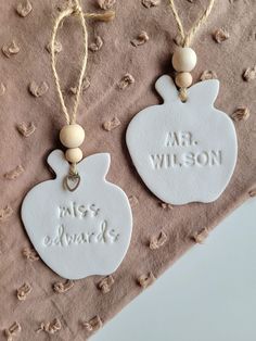 two personalized ceramic ornaments hanging from twine