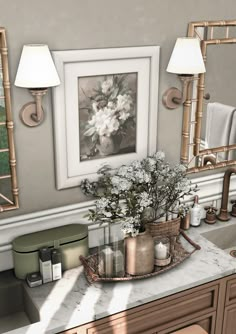 a bathroom vanity with flowers and candles on the counter next to two framed pictures above it