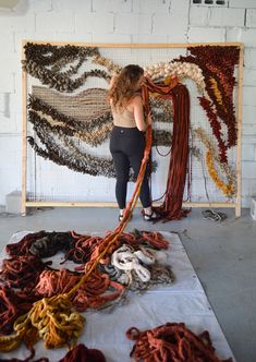 a woman standing in front of an art work with yarn on the floor and behind her