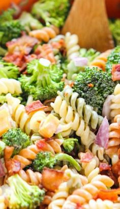 pasta salad with bacon and broccoli in a bowl next to a wooden spoon