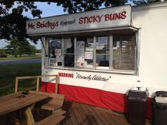 an outside view of a restaurant called sticky buns with picnic table and benches in front