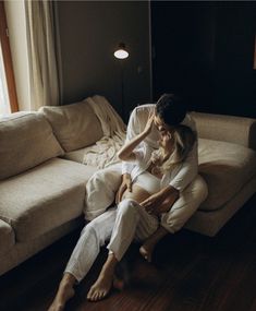 a man and woman are sitting on the floor in front of a couch with their arms around each other